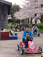 足踏み式ゴーカートに乗るこどもたち