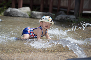 せせらぎで水遊びをするこども